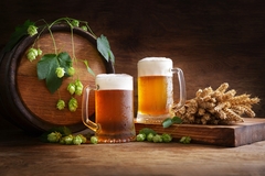 Image two beer glasses and hops against a brown background