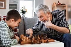 Image An old man beats a child at chess.