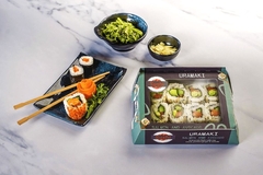 Sushi in paper-based packaging and on plate with chopsticks.