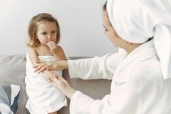 Image A mother putting lotion on her child's arm.