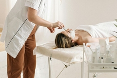 Image A dermatologist using a tool on someone's face.
