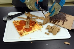 Image A person cutting a pizza box.