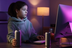 Teenage girl on a computer drinking an energy drink.