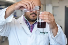 Image A person in a white coat pouring liquid