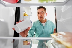 Image Man looking at food in fridge.
