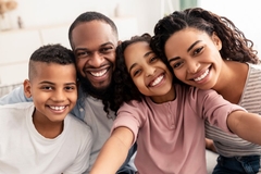 Image A family smiling while at the beach.