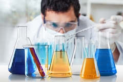Image male scientist looking at colored liquids in flasks