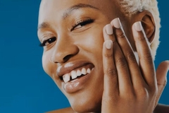 A woman touching her cheek and smiling.