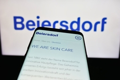 Image Beiersdorf in the background with a phone in front with "we are skin care" written on it.