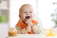 Image Baby enjoying food at table.