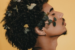 Image man with flowers in his hair against yellow backdrop