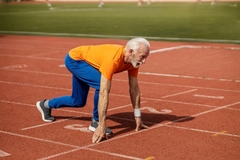 An older gentlemen gets ready to sprint from the starting line.