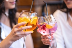 Image two women's hands holding wine glasses with colored liquids