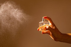 female hand spraying perfume into the air