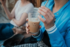 Image a female hand holding cold coffee in a glass