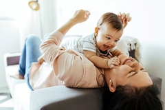 Image baby on mother laying on couch
