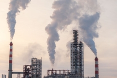 Image A petrochemical plant with smoking coming out of the top.
