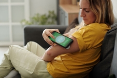 Image Woman checking blood glucose level with her phone