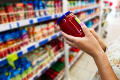 Image A person holding a jar of red sauce.