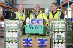 Image three men in flourescent green jackets holding food packets for charity