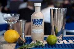 Image A bottle of alcohol next to a silver shaker and fruit.