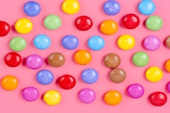 Image Brightly colored candy on a pink background.