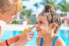 Image mum applying sunscreen to daughter's face
