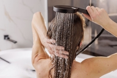 Image woman risning shampoo in bathtub wth water from shower