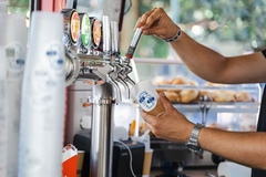 A person pouring a drink from a beer tap