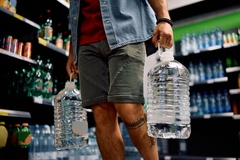 A person holding two large water bottles.