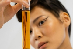 woman holding lab flask with orange liquid