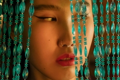 chinese woman looking through beaded curtains