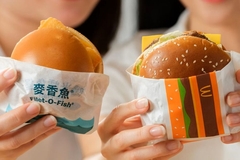 People holding burgers in wrappers