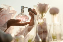 Image hands holding bottle of fragrance in field of flowers
