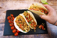a hand holding tacos with minced fungi protein