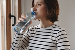 woman drinking water from tethered cap bottle