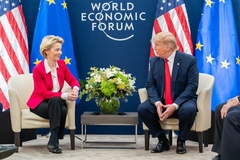 a mature man and woman in formal suits talking  while seated on cream colored chairs