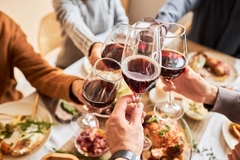 People toasting with red wine at a meal