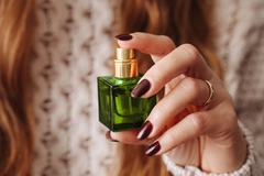 Image A girls hand holding a green bottle of perfume.