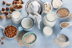 Image variety of plant based drinks with oats and almonds against a light blue background