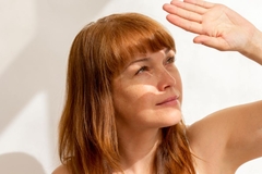 Image A woman shielding her face from the sun.