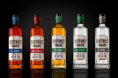 A lineup of five District Made spirits bottles displayed against a black background