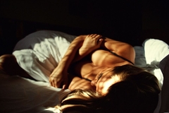 Image A woman lying in bed in her bra.