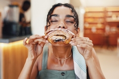 Image A woman biting into a croissant.