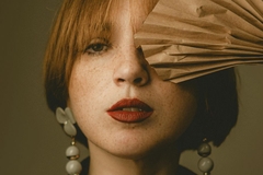 Image woman with red lipstick holding paper over one eye