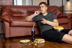Image Young man snacking on junk food in front of the television.