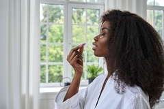 Image A beautiful women prepares to take a supplement in pill form.