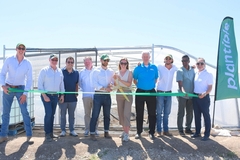 a group of men and women cutting a green ribbon at a construction site