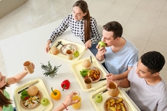 Image People eating around a table in a canteen setting.