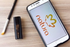 Image A phone with the Natura logo on it next to a makeup brush and lip product.